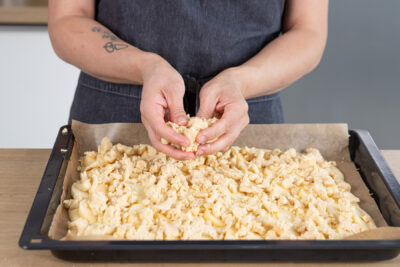 Streusel auf dem Apfelkuchen verteilen