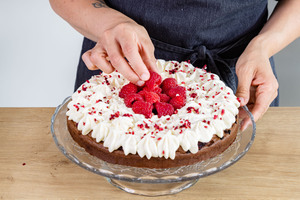 Himbeeren auf der Brownie-Himbeer-Torte verteilen