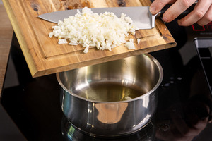 Zwiebel und Knoblauch in den Topf geben