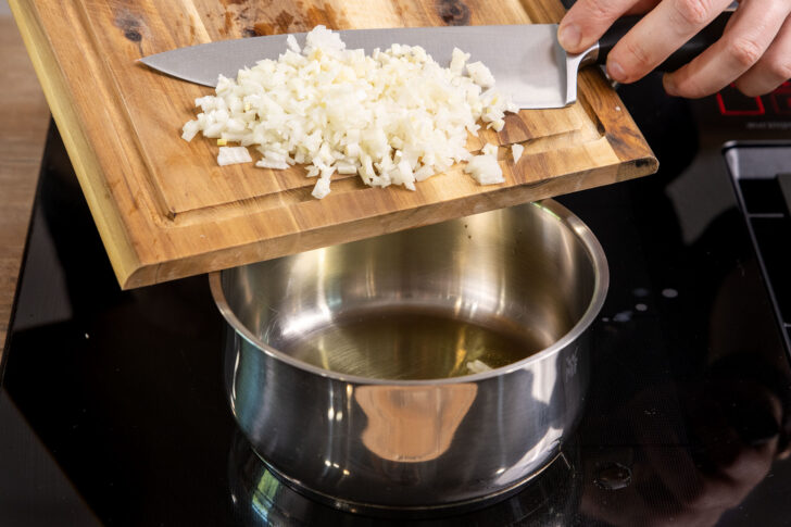 Zwiebel und Knoblauch in den Topf geben