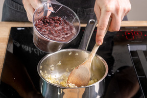 schwarze Bohnen zum Knoblauch und zur Zwiebel geben