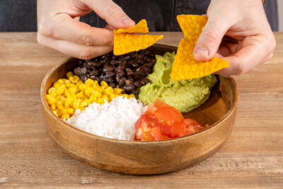 Tortilla-Chips zur Burrito-Bowl geben