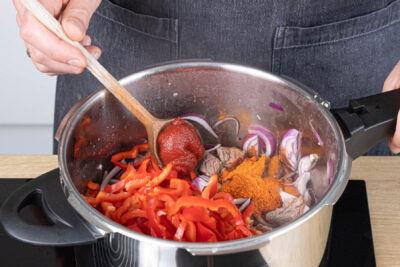 Geschnittenes Gemüse, Tomatenmark und Gewürze anschwitzen