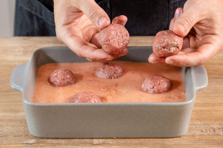 Hackfleischbällchen in die Tomatensoße geben