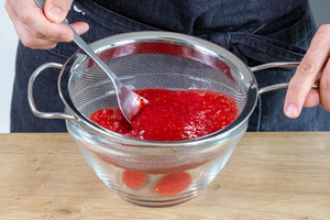 pürierte Himbeeren durch ein Sieb geben