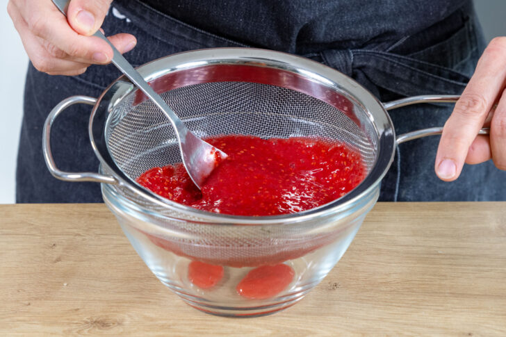 pürierte Himbeeren durch ein Sieb geben