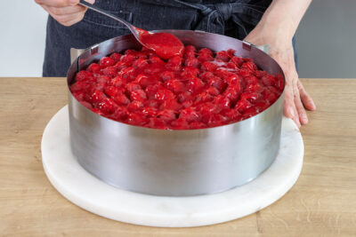 Himbeer-Guss über der Himbeer-Mascarpone-Torte verteilen
