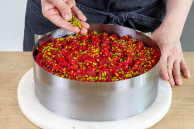 Pistazien über die Himbeer-Mascarpone-Torte geben