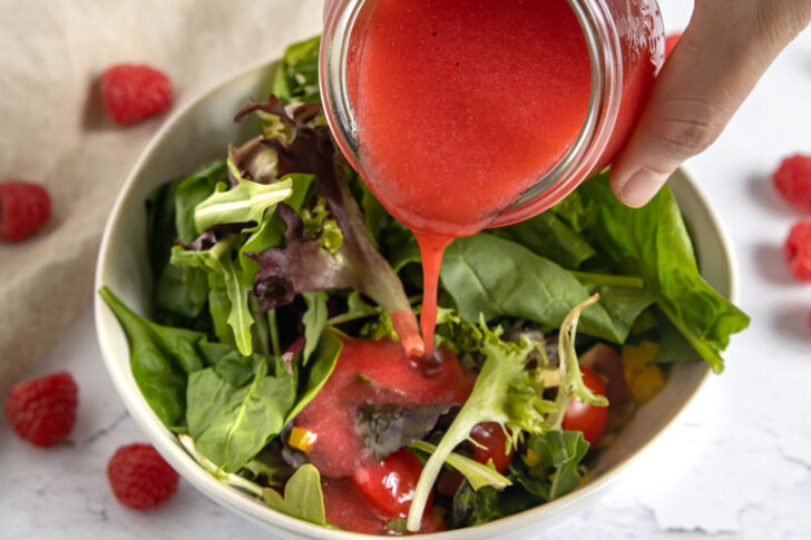 Himbeer-Vinaigrette über Salat gießen