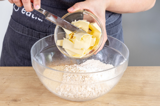 Butter zum Zucker, Mehl, Zimt und den Haferflocken geben
