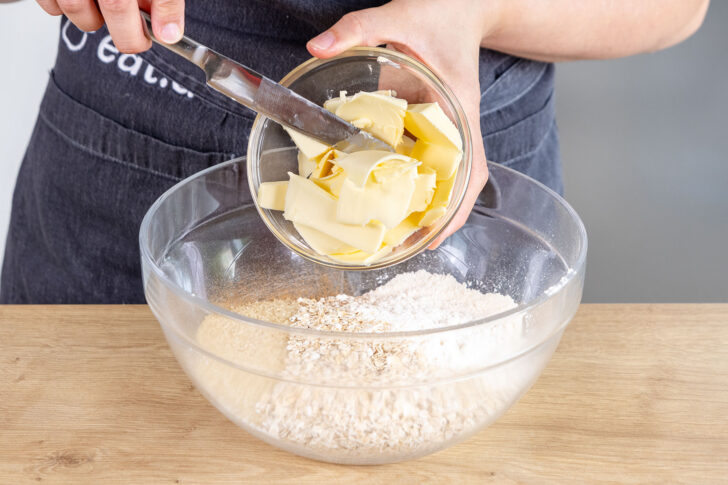 Butter zum Zucker, Mehl, Zimt und den Haferflocken geben
