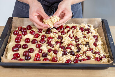 Streusel über den Kirschkuchen streuen