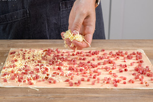Blätterteig mit Schinkenwürfeln und Käse belegen