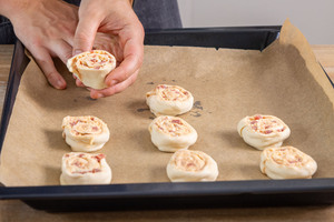 Pizzaschnecken mit Blätterteig auf Backblech verteilen