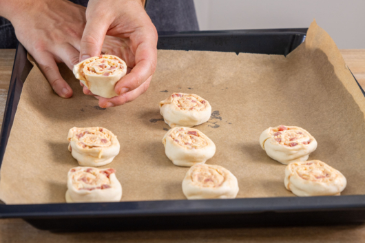 Pizzaschnecken mit Blätterteig auf Backblech verteilen