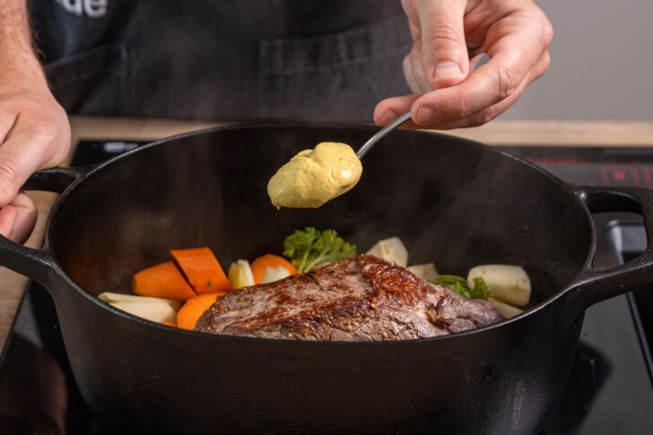 Senf zum Fleisch in den Bräter geben