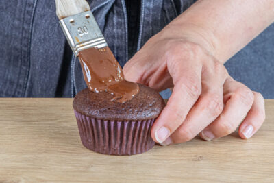 Schoko-Muffins ohne Eier mit Schokolade bestreichen