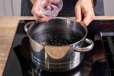 Wasser zu den schwarzen Johannisbeeren geben