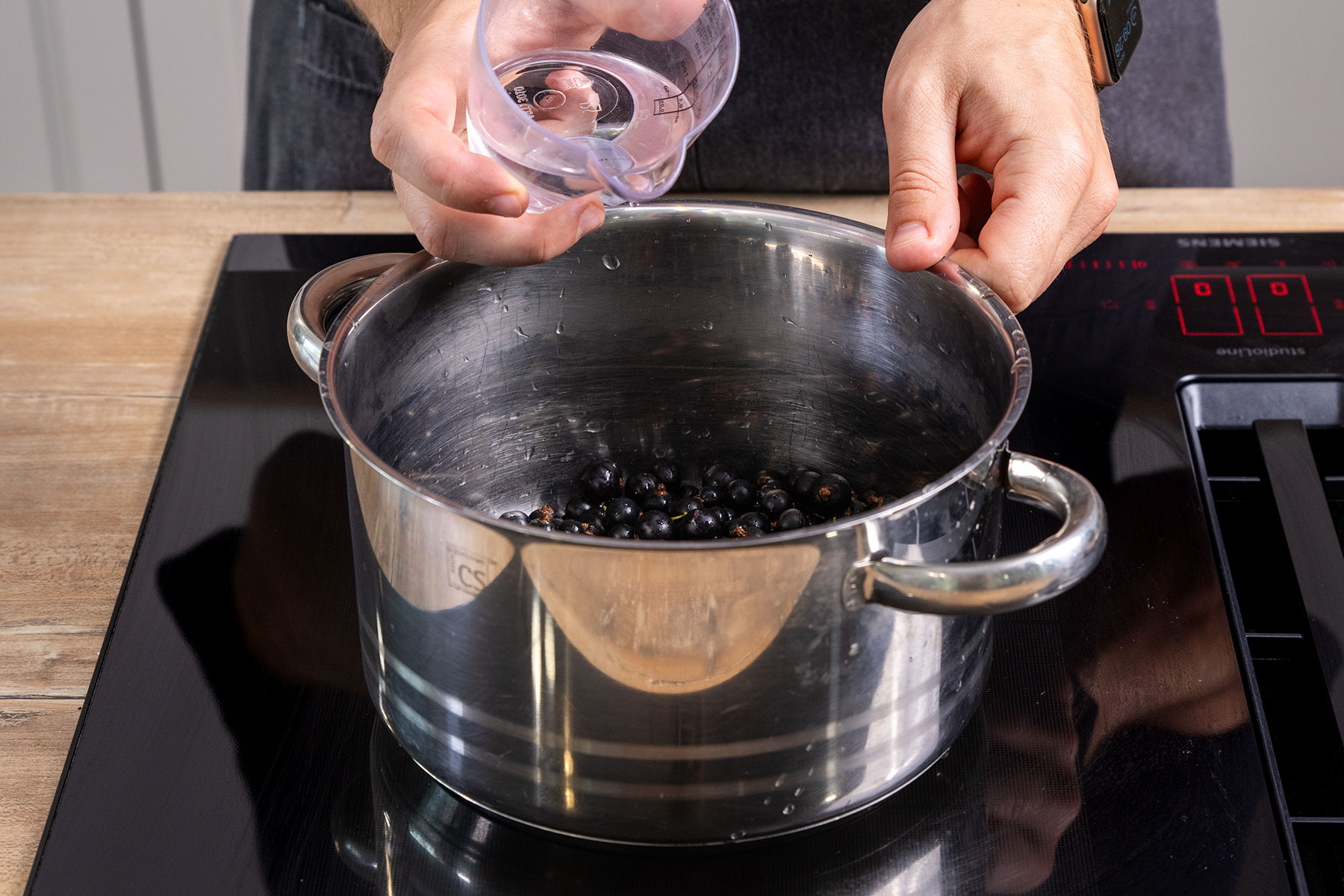 Wasser zu den schwarzen Johannisbeeren geben