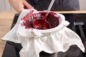 pürierte schwarze Johannisbeeren durch ein Passiertuch geben
