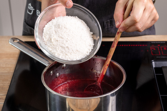 Gelierzucker zu der schwarzen Johannisbeermarmelade ohne Kerne geben