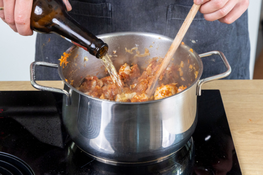 Bier zu dem Schweinegulasch nach Omas Rezept gießen