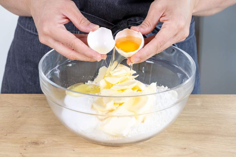 Eier zu Mehl, Zucker, Backpulver, Zucker und Butter in eine Schüssel geben