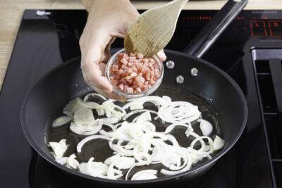 Zwiebelringe und Schinkenwürfel anbraten