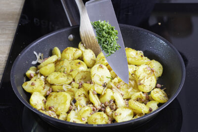 Bratkartoffeln mit Speck und Zwiebeln mit Petersilie würzen
