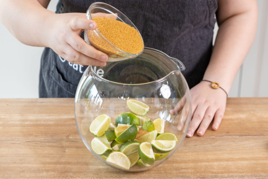 Braunen Zucker über die Limetten geben