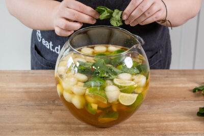Minze zur Caipirinha-Bowle mit Pitu geben