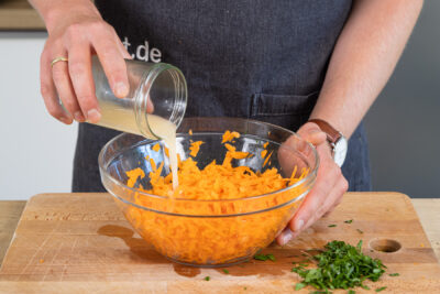 Dressing zu dem Karottensalat geben