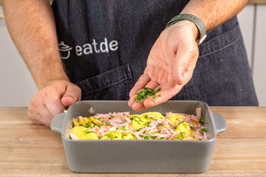 Petersilie über Kartoffel-Schinken-Gratin geben