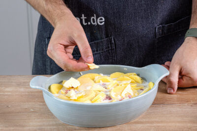 Butterflocken über Kartoffelgratin mit Speck geben