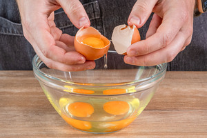 Eier in eine Schüssel schlagen