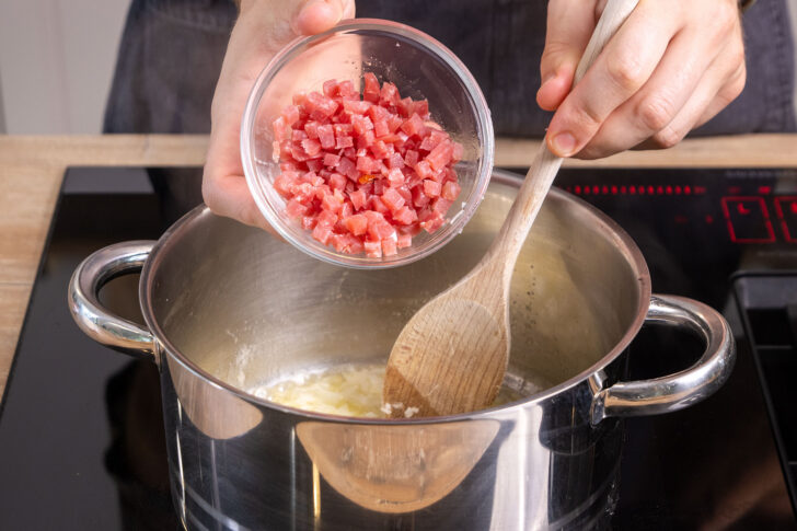 Schinkenspeckwürfel in den Topf geben