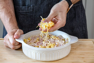 Nudelauflauf mit Schinken mit Käse bestreuen