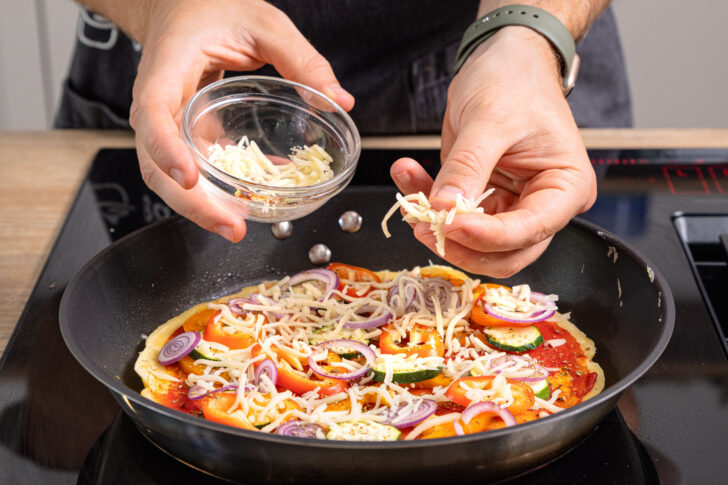 Pfannenpizza mit Käse bestreuen