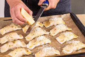 Parmesan über Schinken-Käse-Taschen reiben