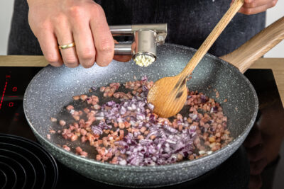 Zwiebel und Knoblauch in Pfanne geben