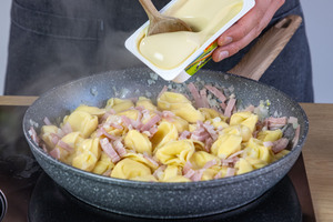 Schmelzkäse zu den Tortellinis geben