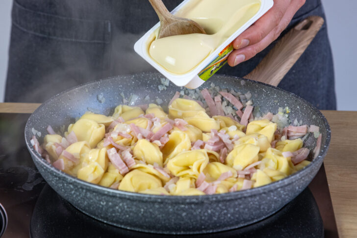 Schmelzkäse zu den Tortellinis geben