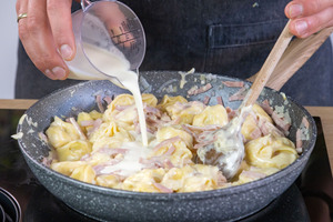 Sahne zu den Tortellinis gießen
