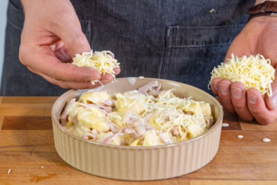 Tortellini-Auflauf mit Schinken-Käse-Sahne-Soße mit Käse bestreuen
