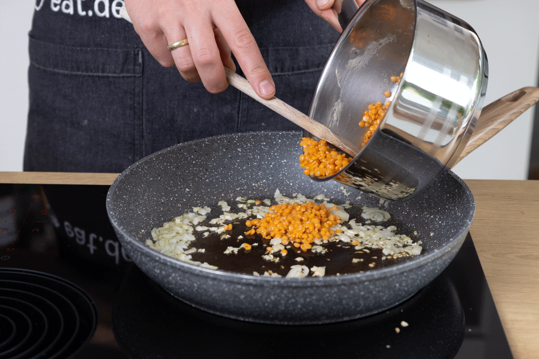 Olivenöl in einer Pfanne erhitzen, Knoblauch und Zwiebeln darin anbraten. Vorgegarte rote Linsen mit der Flüssigkeit dazu geben.
