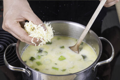 Schmelzkäse sowie Gouda in die Suppe geben und schmelzen