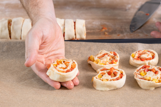 Vegetarische Pizzaschnecken auf dem Backblech verteilen