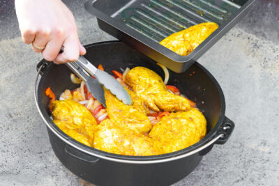 Hähnchen wieder in den Dutch Oven zu dem Paprika geben.