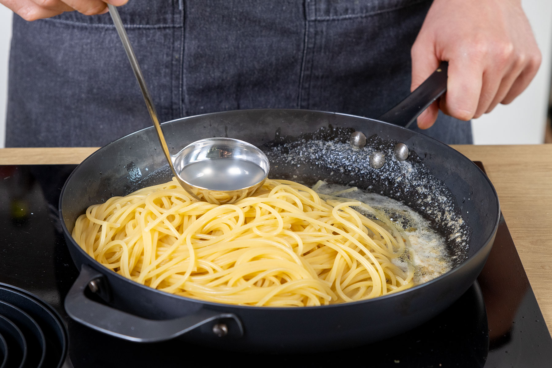 Pastawasser zu den Spaghetti geben