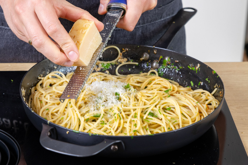 Parmesan über die Pasta mit Sardellen reiben
